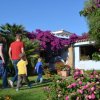 Persone camminano verso una casa con fiori colorati.