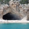 Spiaggia con grotte e persone, acqua azzurra.