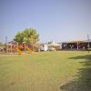 Un parco giochi con scivoli e altalene su un prato, vicino a un teatro all'aperto.