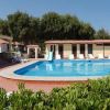 Piscina all'aperto circondata da lettini, vegetazione e case vacanza.