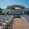 Palco all'aperto con sedie bianche disposte in file.