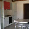 Cucina moderna con tavolo, sedie e mobile rosso sopra i fornelli.