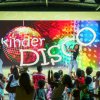 Bambini che ballano su un palco illuminato con scritta 