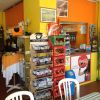 Interno di un negozio colorato con scaffali di snack e bibite, sedie e tavoli.