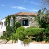 Casa in pietra con tetto a spiovente e giardino rigoglioso, cielo limpido.