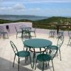Tavoli e sedie di metallo su una terrazza con vista sul mare.