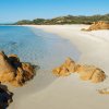Spiaggia di sabbia bianca e rocce marroni.