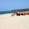 Spiaggia sabbiosa con sdraio e ombrelloni arancioni.