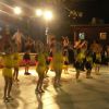 Bambini in costume giallo e nero che ballano su un palco illuminato la sera.