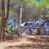 Tenda grigia e verde tra gli alberi, staccionata a vista.