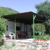 Casa con veranda in metallo verde, circondata da piante e fiori.