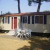 Casa mobile chiara con porte marroni e sedie bianche in un cortile sabbioso.