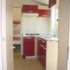 Una cucina compatta con mobili rossi e beige, piano cottura e lavello, in un piccolo spazio.
