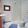 Bagno con doccia circolare, lavandino e WC bianchi.